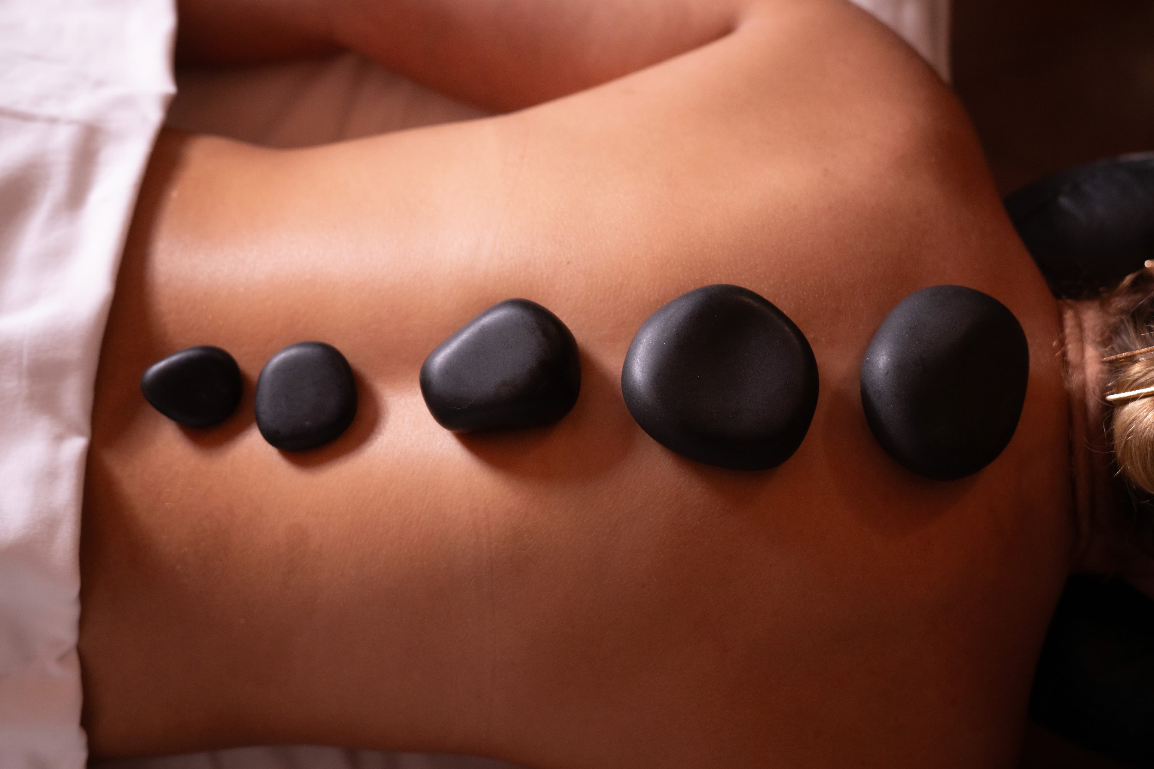 Massagem com pedras quentes nas costas no spa da pousada