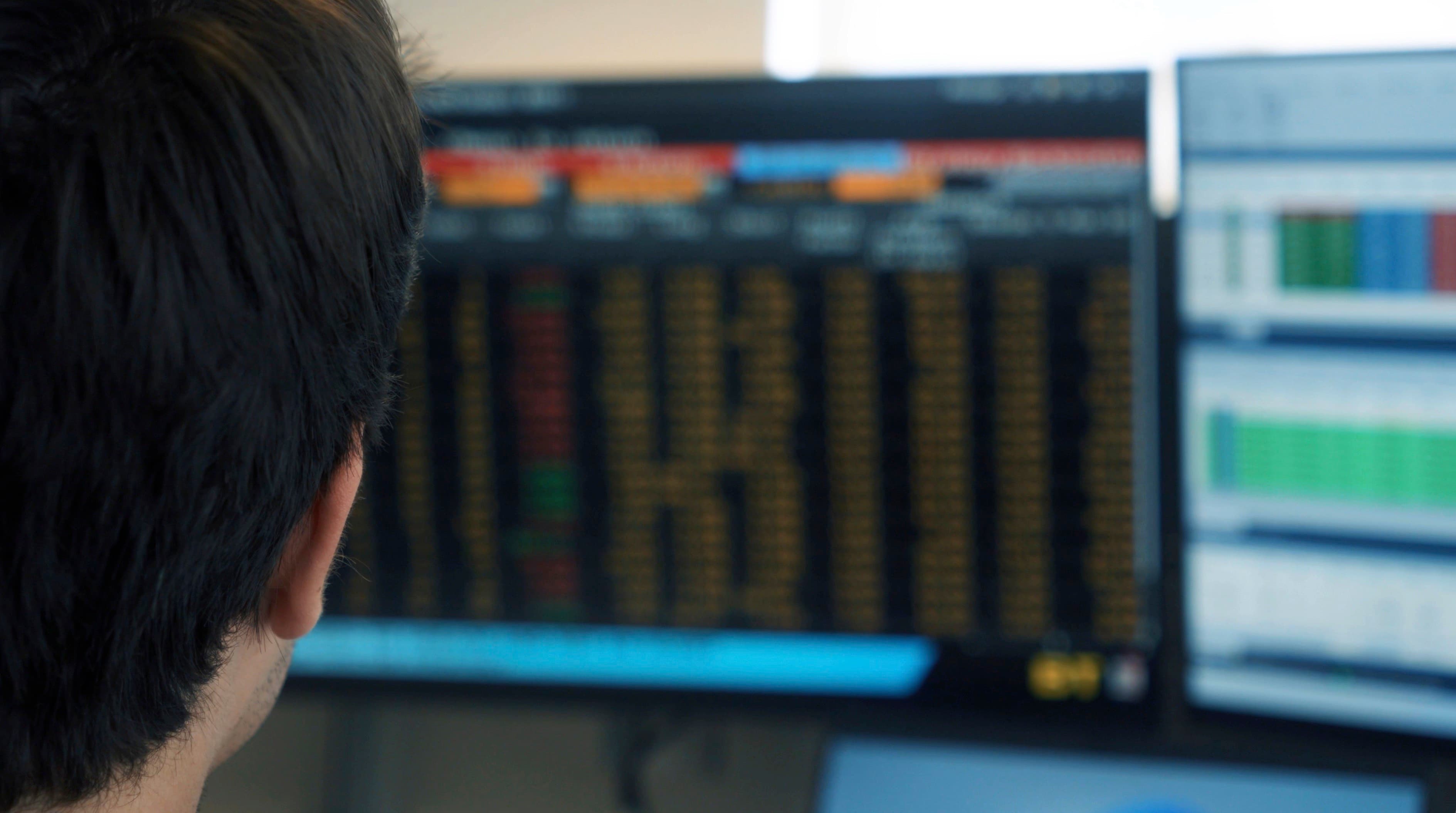 Analista diante de telas com gráficos do mercado financeiro